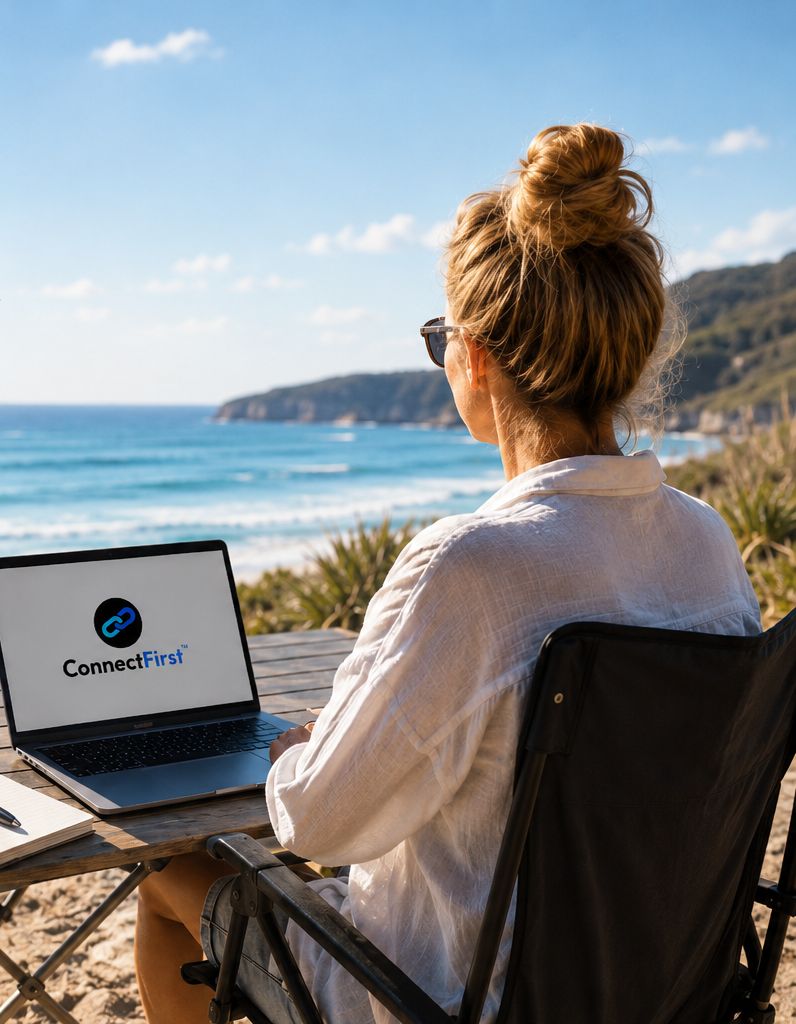 A practitioner working on a laptop at an outdoor table overlooking the beach